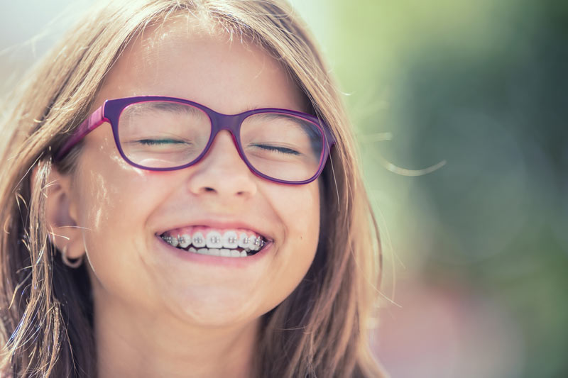 Smiling young girl with purple glasses and braces