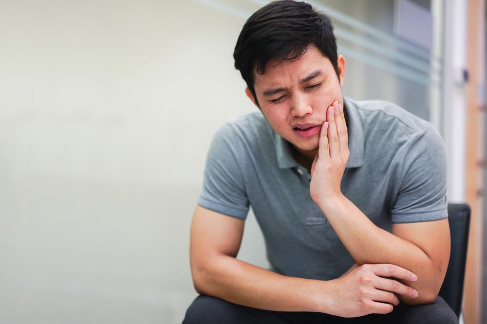 Man of Asian decent suffering from TMJ jaw pain