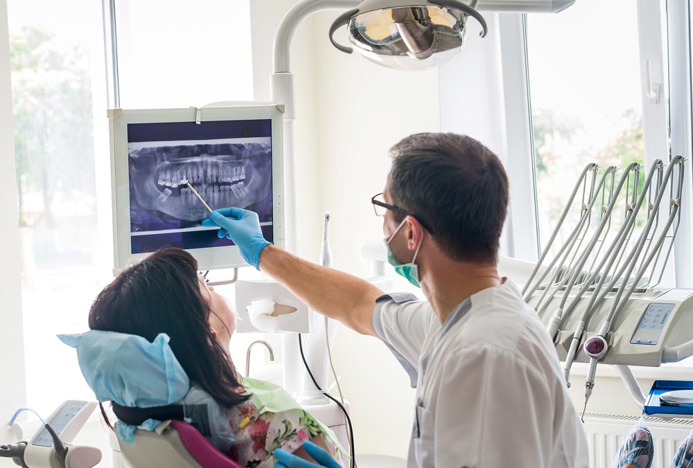 Dentist explaining x-ray photo to a patient in an exam room