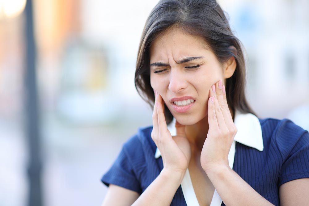 Woman suffering from the pain of TMJ in her jaw