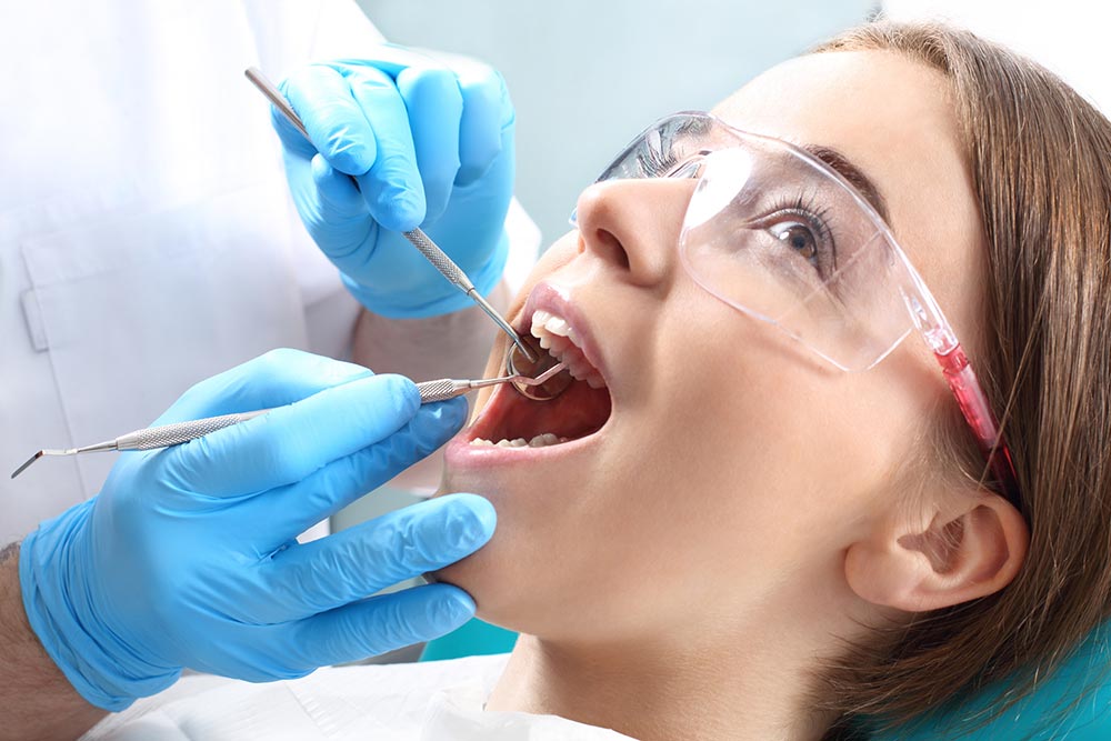 Young woman getting a teeth cleaning at a dentist office.